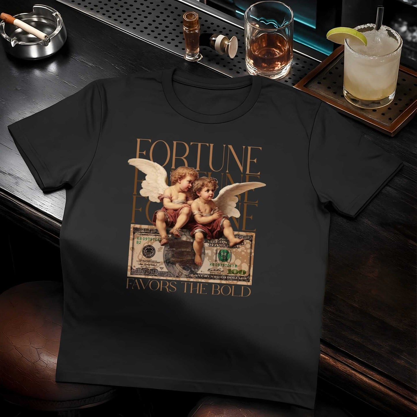 Black t-shirt featuring two winged angels over distressed hundred dollar bill with gold "FORTUNE FAVORS THE BOLD" lettering