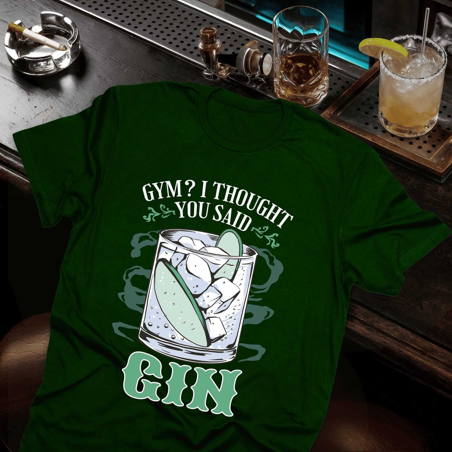Green shirt displaying cocktail glass with a gin, lime, and ice, "Gym? I Thought You Said Gin" slogan in playful font