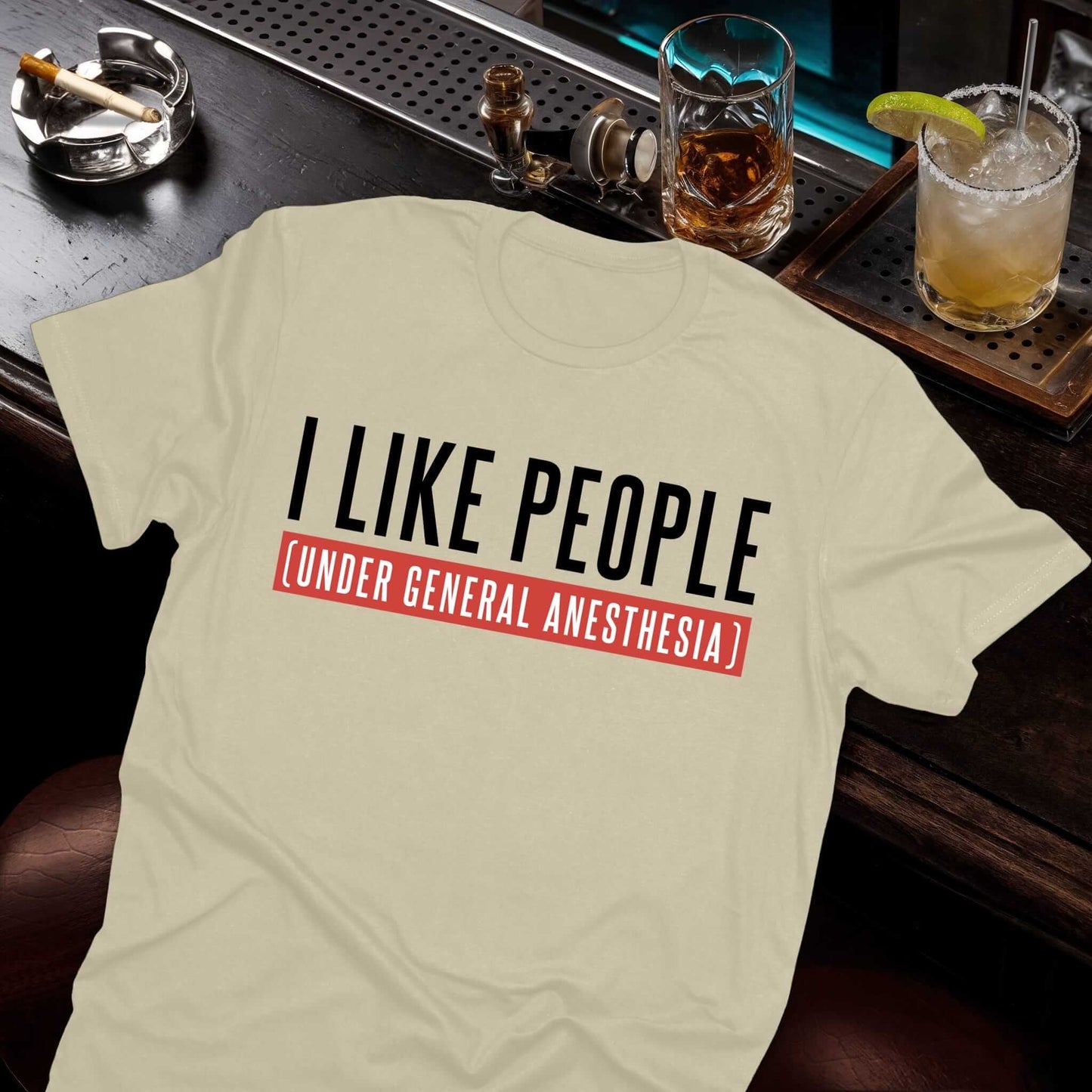 Beige shirt featuring medical humor about doctors' workdays with clean text "I LIKE PEOPLE - UNDER GENERAL ANESTHESIA."