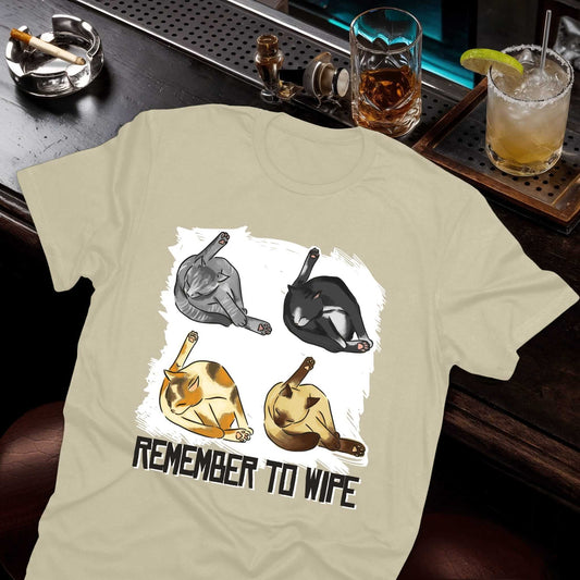 Remember To Wipe design featuring four adorable cats in self-cleaning poses with brushed white background effect on beige tee