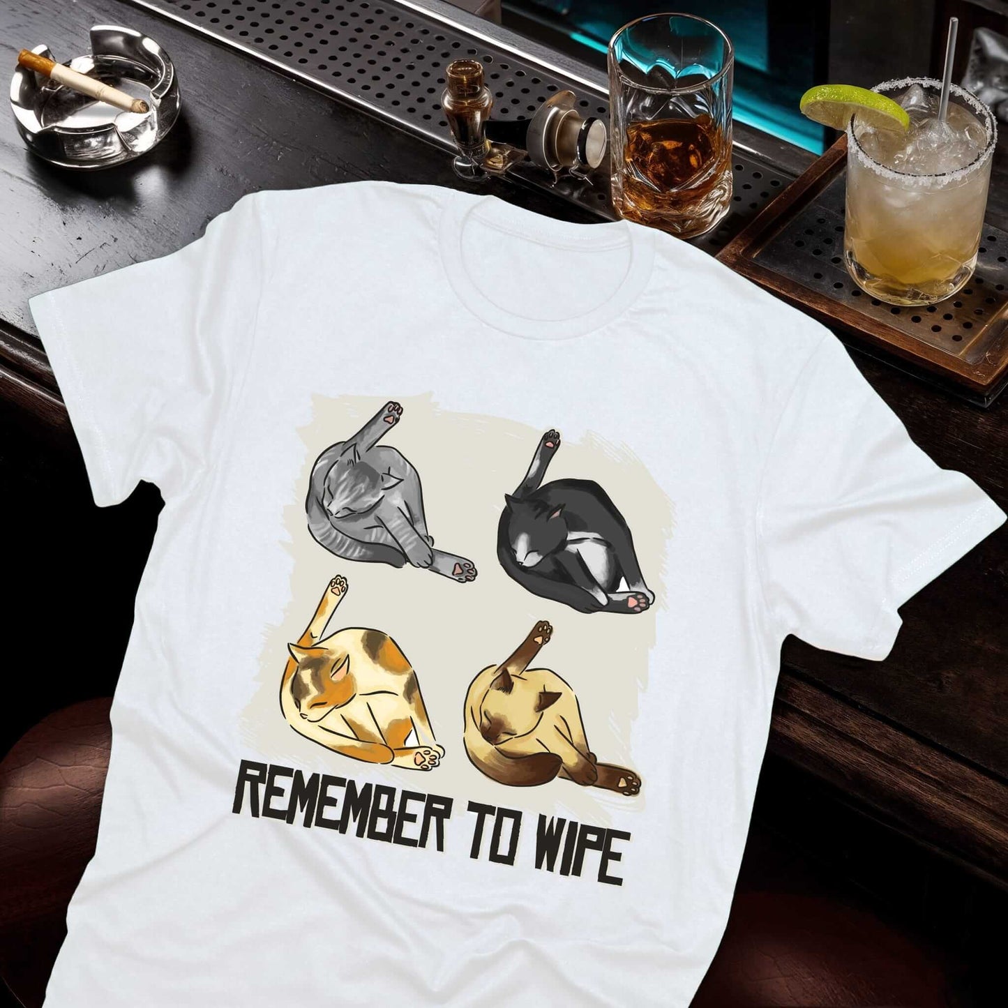 Four cartoon cats in grooming positions - gray tabby, black, orange, and tan cats cleaning themselves on white t-shirt