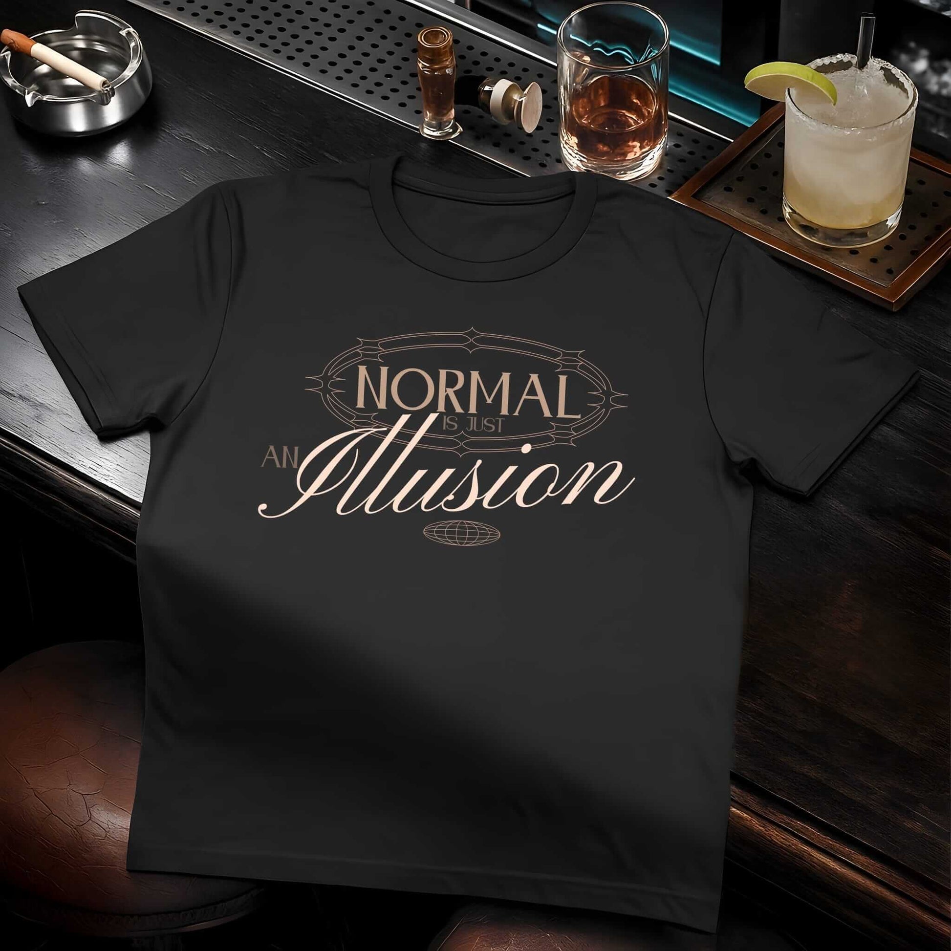 Golden-brown text reading 'NORMAL Is an Illusion' with decorative flourishes in vintage-inspired typography on black t-shirt.