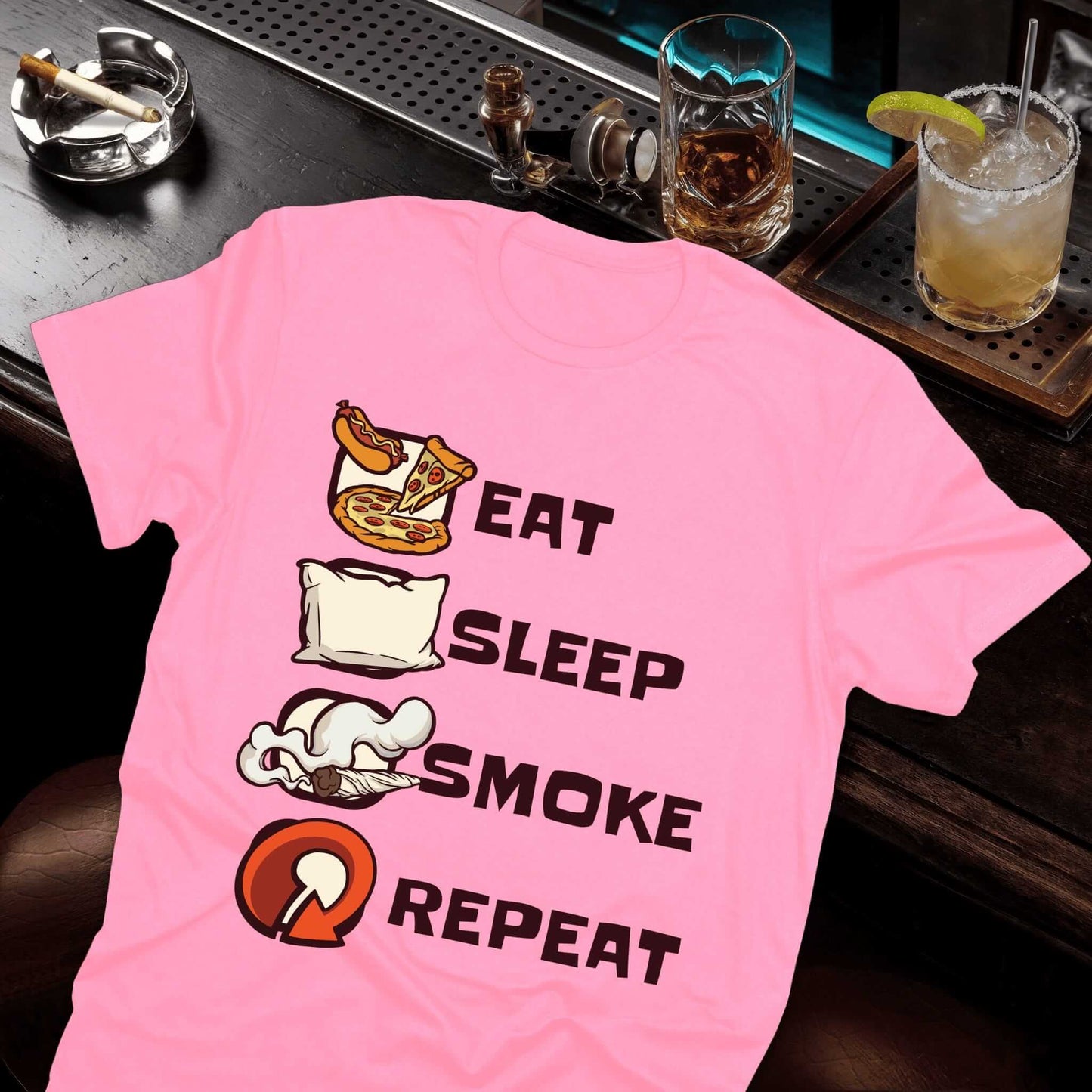 Pink t-shirt featuring four lifestyle icons (pizza, pillow, skull, ashtray) with bold "Eat Sleep Smoke Repeat" text design