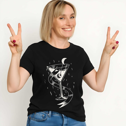 White line art cocktail glass with crescent moon and flowing ribbon elements on black women's t-shirt
